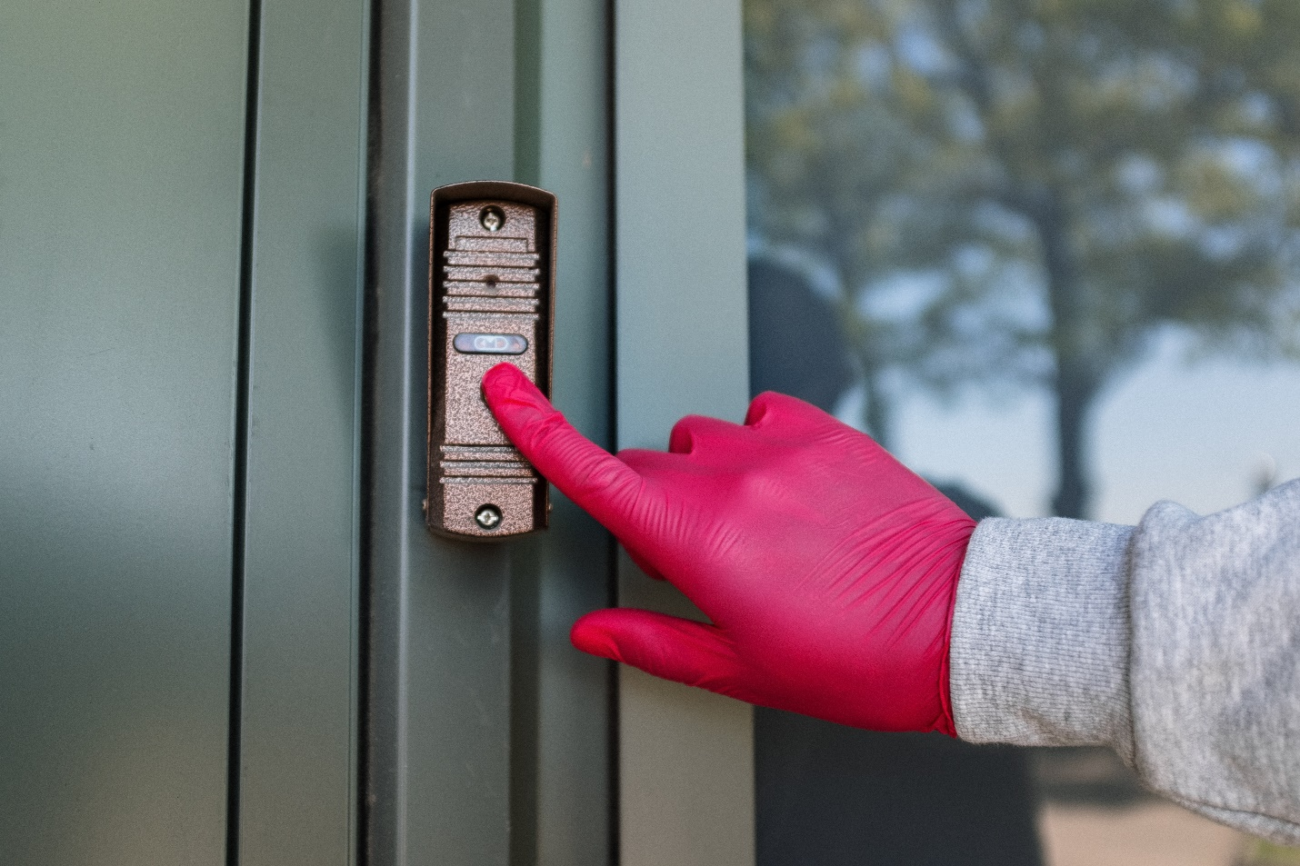 A person rings the bell on a grey door