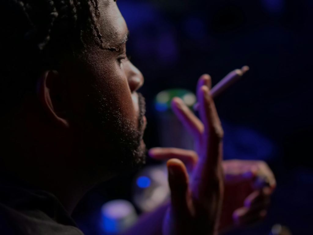 A bearded man holds a joint against a dark background, illustrating the allure of cannabis pre-rolls in the world of recreational enjoyment.