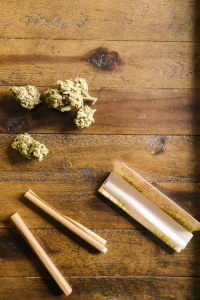 Cannabis flower with rolling paper on a wooden surface, symbolizing personalized cannabis use and premium pre-roll selection