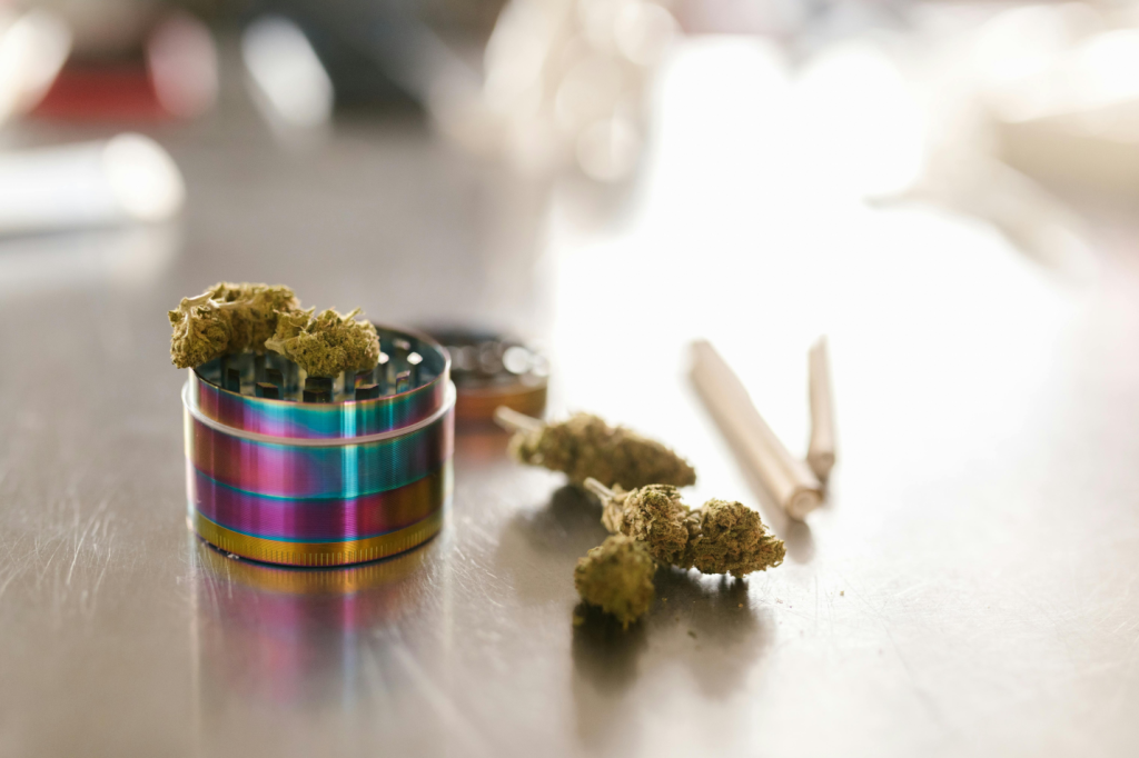 Cannabis buds and a metal grinder on a table