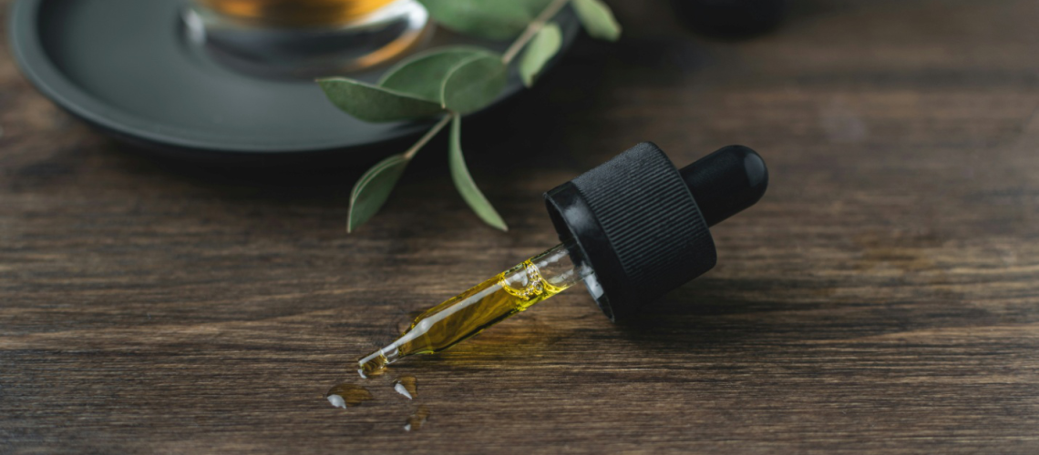 a dropper with CBD oil set on a wooden surface