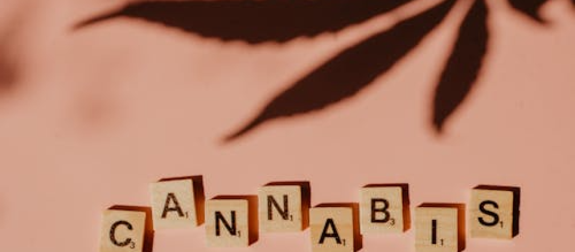 Scrabble tiles spelling “CANNABIS” on a bright pink surface